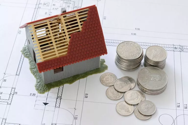 miniatur haus neben münzen